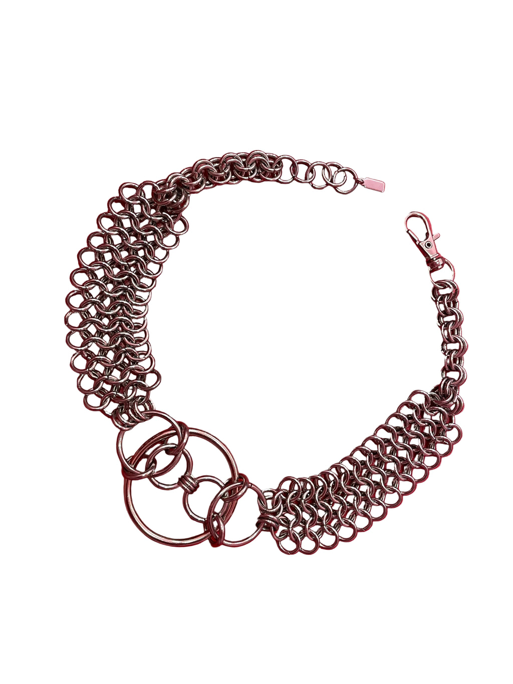 A close-up of a chain mail choker featuring intricate metal links, with bold O-rings positioned at the center. The choker rests elegantly on a neutral backdrop, highlighting its edgy, industrial design.
