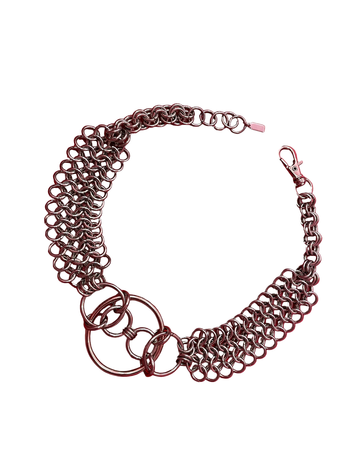 A close-up of a chain mail choker featuring intricate metal links, with bold O-rings positioned at the center. The choker rests elegantly on a neutral backdrop, highlighting its edgy, industrial design.