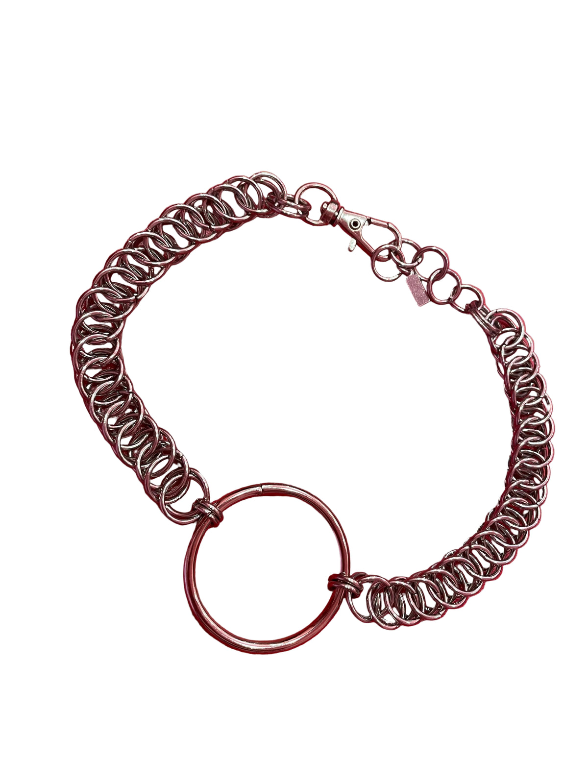 A close-up of a simple silver chain choker with a bold ring at the center. The sleek, minimalist design rests elegantly against a neutral backdrop, highlighting its refined and timeless appeal.