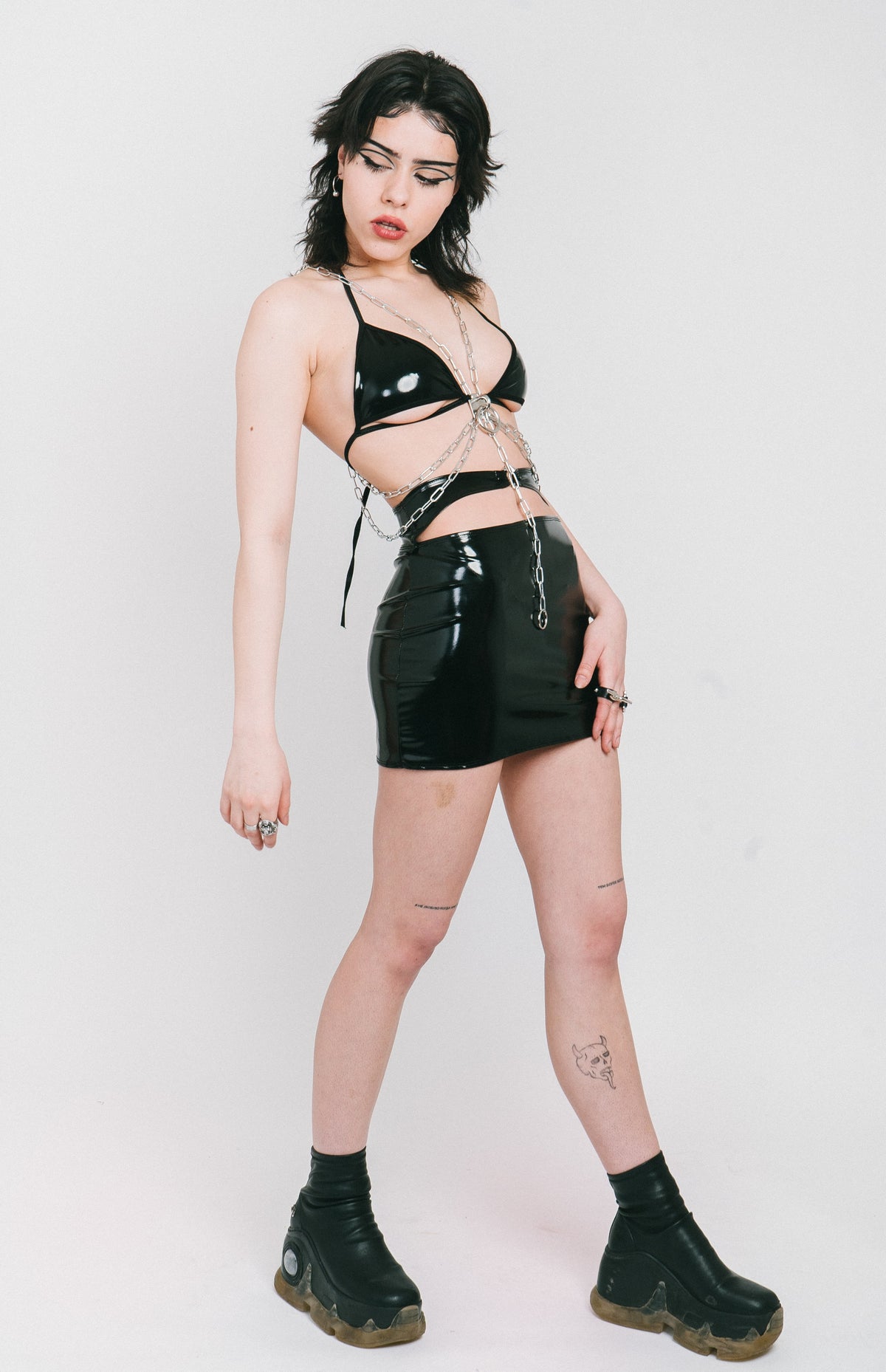 Black vinyl mini skirt with silver piercing closure.